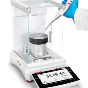 Explorer 2025 model, Semi-Micro Balance, Plus EXP, with pipette calibration chamber in situ, balance turned on and being used, viewed side on, white background.