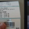 BTT Checkweighing scale second closup of labels with human hand holding them up to camera.